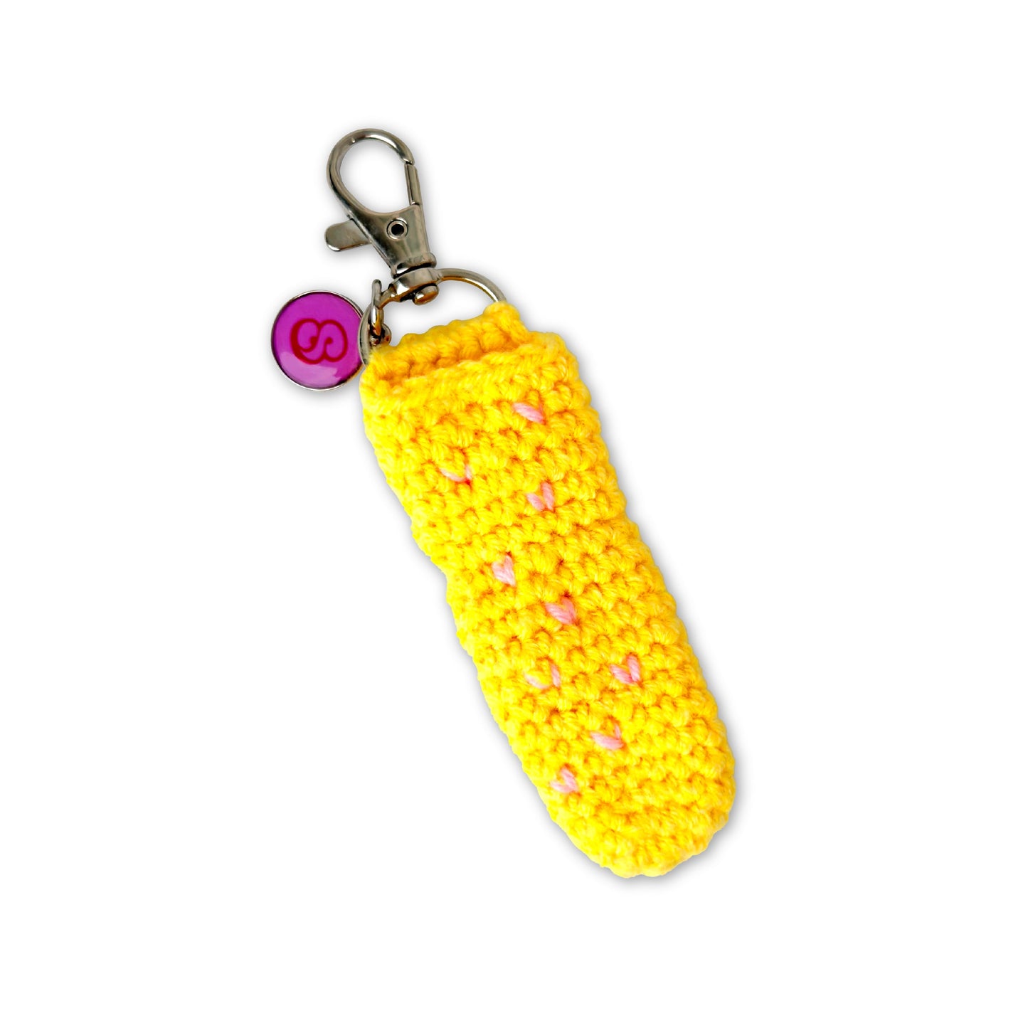 Yellow crocheted keychain with pink heart patterns on a white background
