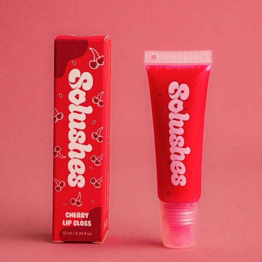 Cherry lip gloss tube and packaging with 'Solushes' branding on a pink background