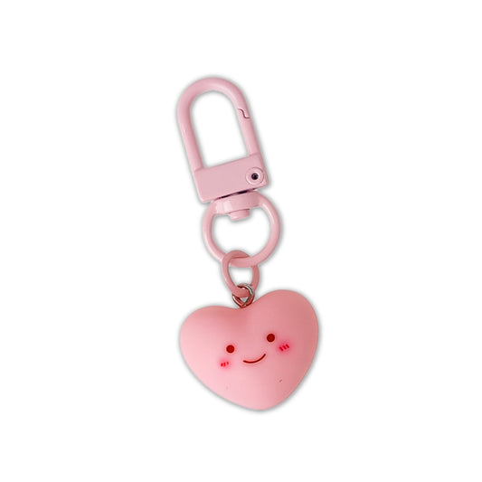 Pink heart-shaped keychain with a smiley face on a white background